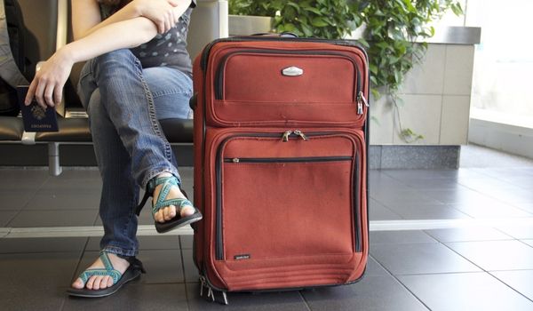 A person sitting next to a suitcase